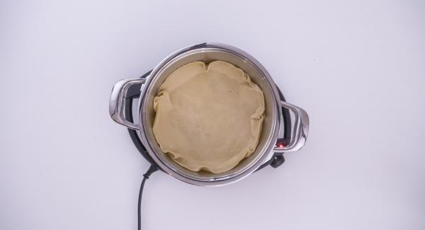 As soon as Audiotherm beeps on reaching the roasting window, insert the baking paper into the pot. Place the puff pastry onto the baking paper and pour the spinach and cheese mixture into it. Push back into the pie any protruding pastry from the edges.