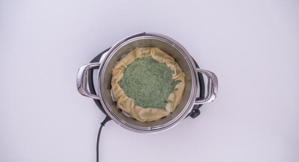 As soon as Audiotherm beeps on reaching the roasting window, insert the baking paper into the pot. Place the puff pastry onto the baking paper and pour the spinach and cheese mixture into it. Push back into the pie any protruding pastry from the edges.