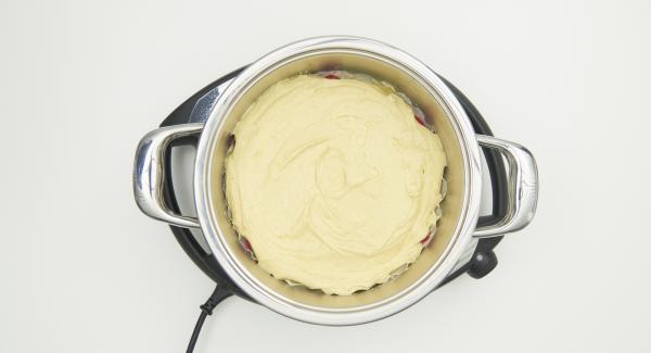 Spread the drained pineapple on the baking paper and fill the gaps with drained cherries, spread the dough over it.