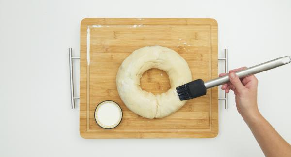 Roll up everything from the long side, form into a wreath and place in the pot with the baking paper. Cut the wreath with scissors on the surface, brush with milk and sprinkle with sugar and almond flakes.