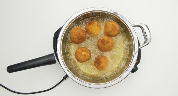 As soon as the Audiotherm beeps on reaching the roasting window, set at level 3, pour the rice balls into the oil and cover with the lid. Deep-fry with the help of the Audiotherm until the turning point at 90 °C is reached. Turn the balls over and deep-fry until they are golden brown, remove them and let them drip off on kitchen paper.