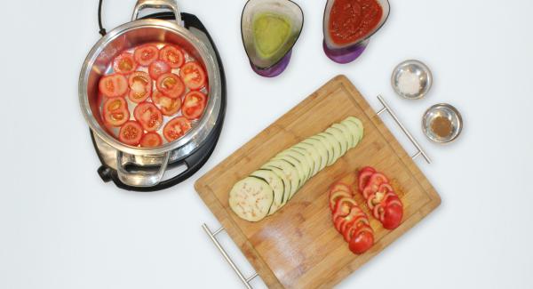 Layer half quantity of the tomato slices inside the pot, then half of the eggplant slices. Season with salt and pepper, then add half of the tomato sauce.