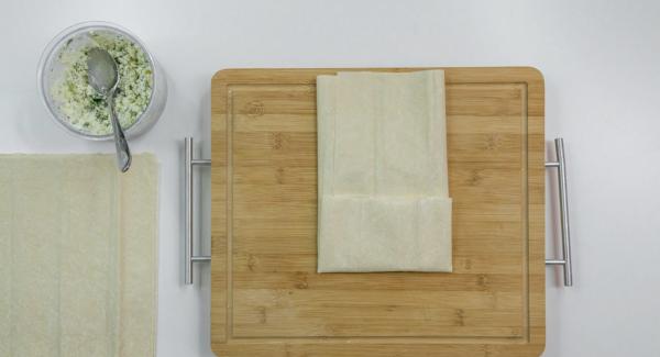 Place 2 sheets of yufka dough on top of each other and spread some Feta mixture on top. Fold the top and bottom sides in the middle. Fold over the right side, lay the left side over it and fix it with a little water.