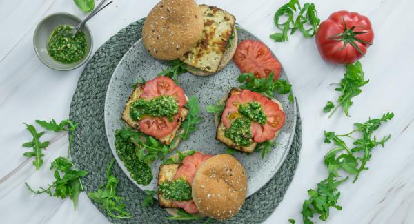 Toast buns a bit and spread with pesto. Top with tomatoes and tofu and serve immediately.