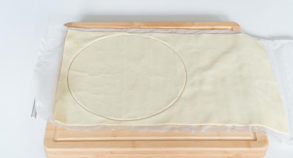 Cut out a round dough sheet with the help of a lid 24 cm.