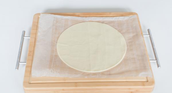 Cut out a round dough sheet with the help of a lid 24 cm.